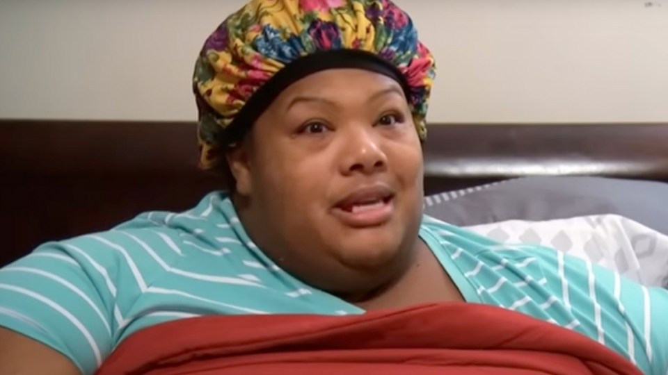 Woman in a floral shower cap and striped shirt speaks.