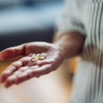 A close up of a person's hand holding supplements or medication