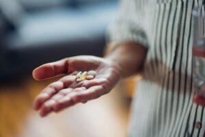 A close up of a person's hand holding supplements or medication
