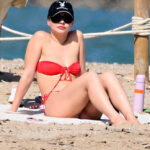 Madelyn Cline in a red bikini on a beach.
