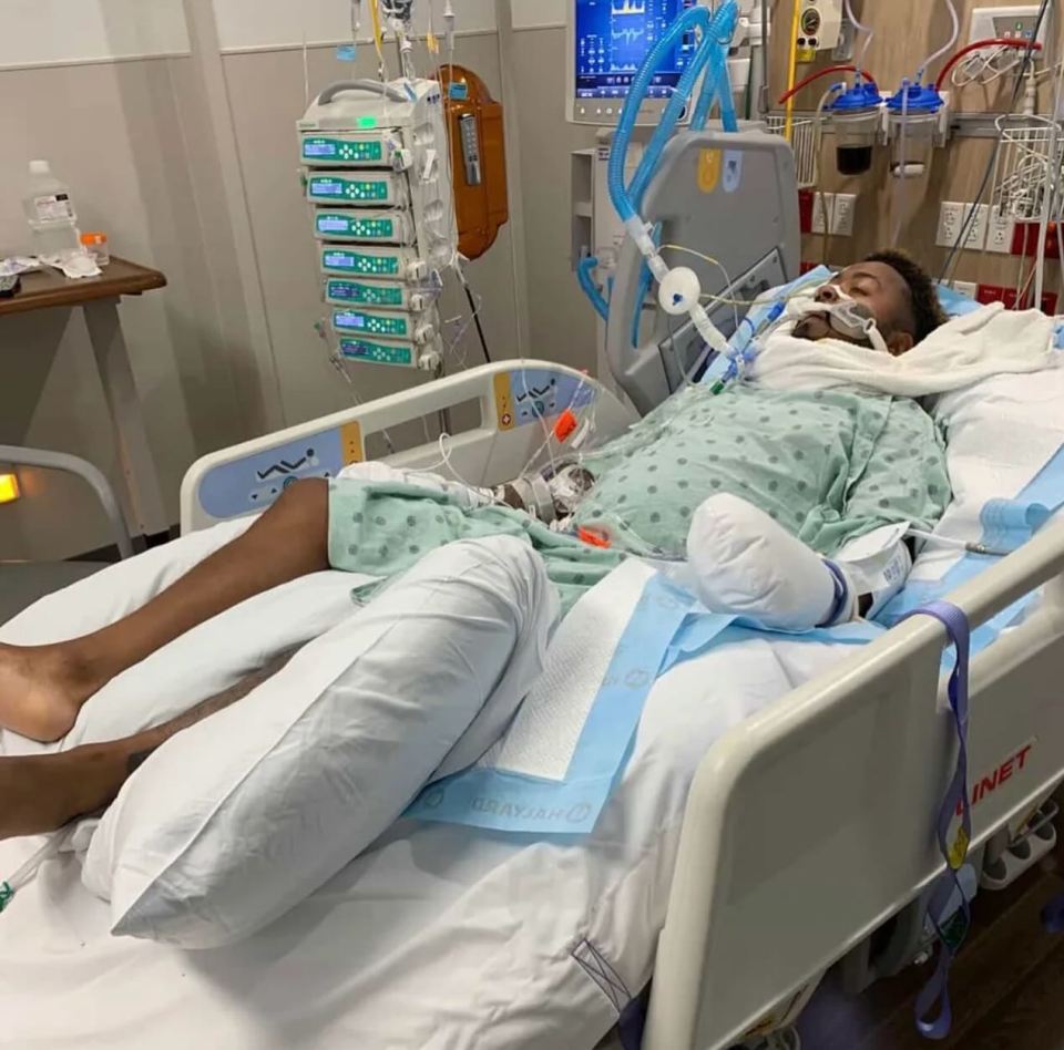 Man in hospital bed receiving medical treatment.