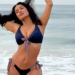 Salma Hayek in a dark blue and gray bikini on a beach.