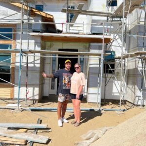 Couple standing in front of a house under construction.