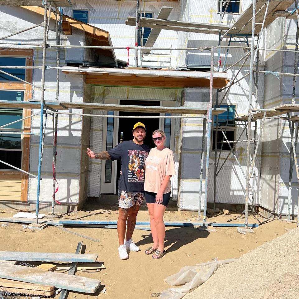 Couple standing in front of a house under construction.