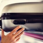 airplane passenger removing suitcase from luggage compartment