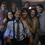 Tony Todd sitting on the set of Final Destination: Bloodlines, surrounded by the lead cast and directors Zach Lipovsky and Adam B. Stein, all smiling at the camera