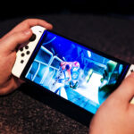A pair of hands holding the Nintendo Switch OLED