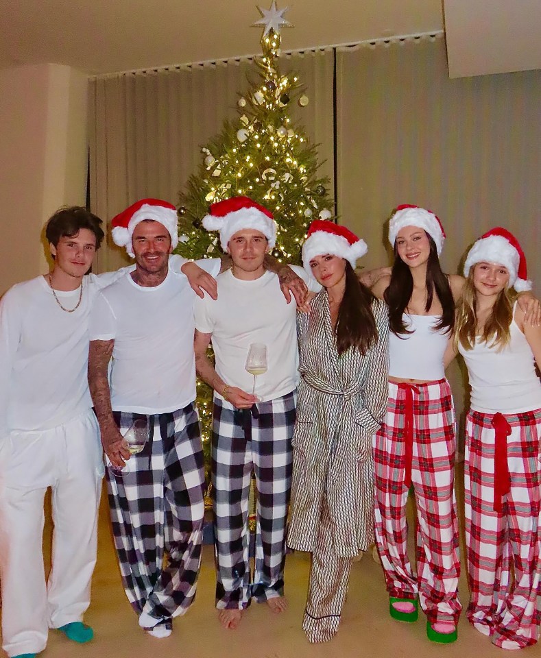 The Beckham family in matching Christmas pajamas in front of a Christmas tree.