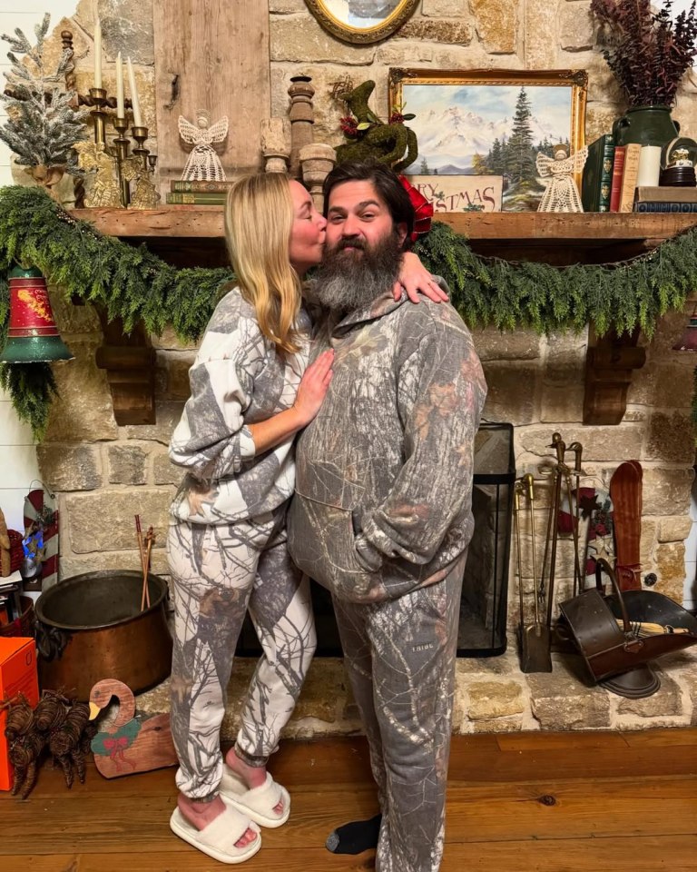 Jessica and Jep Robertson in camouflage pajamas by a fireplace.