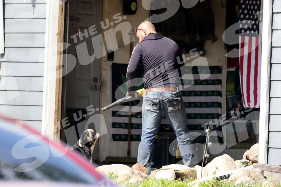Man using leaf blower outside home with dog.