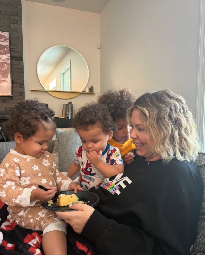 Woman sharing cake with three young children.