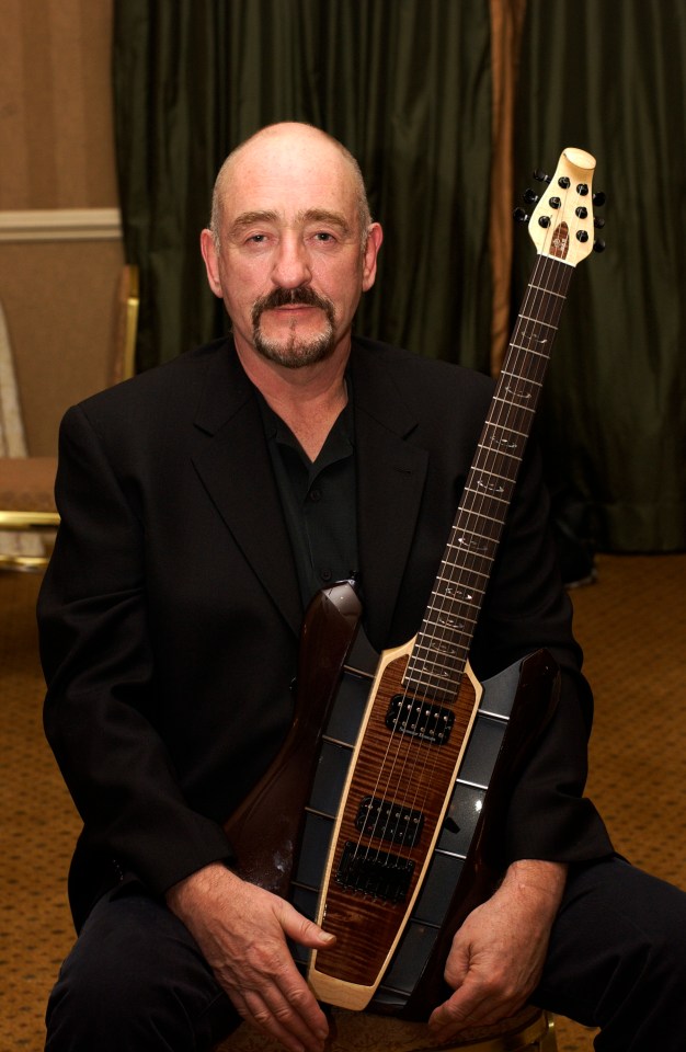 Dave Mason posing backstage with a guitar.