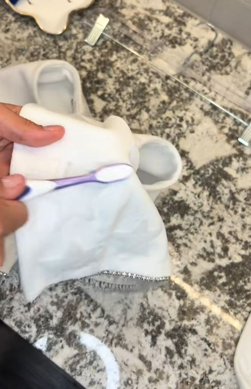 Cleaning a white garment with a toothbrush.