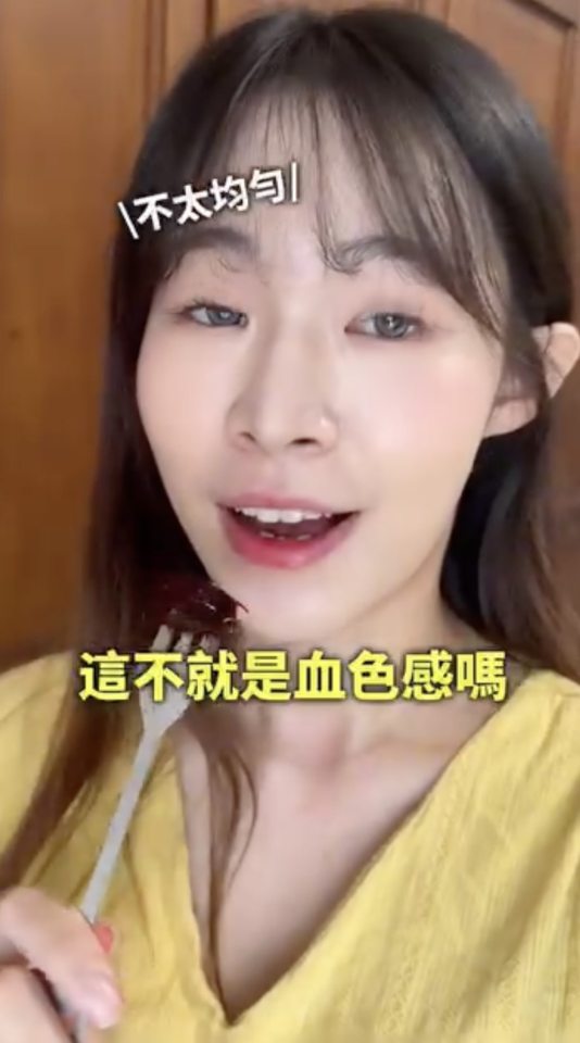 A woman tasting and reviewing a dark-colored cosmetic product.