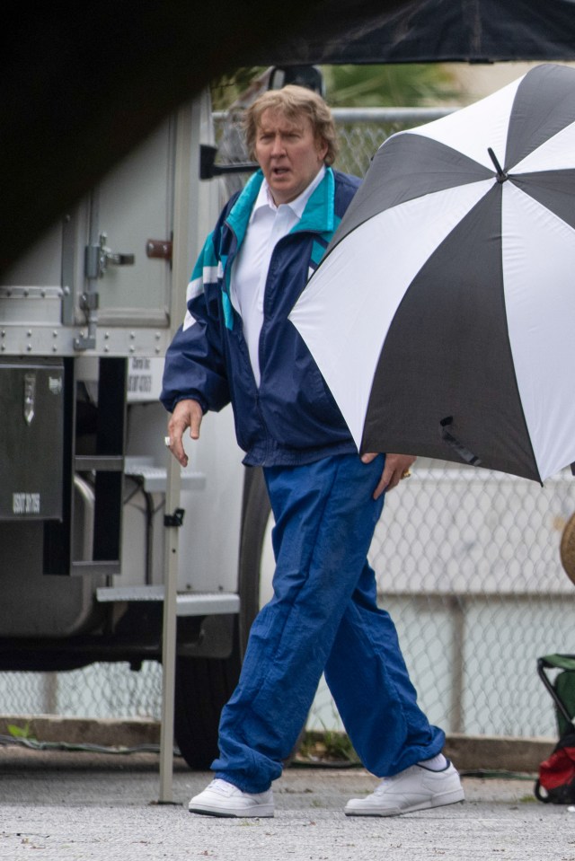 Nicolas Cage on the set of the film *Madden*, wearing a tracksuit and carrying an umbrella.