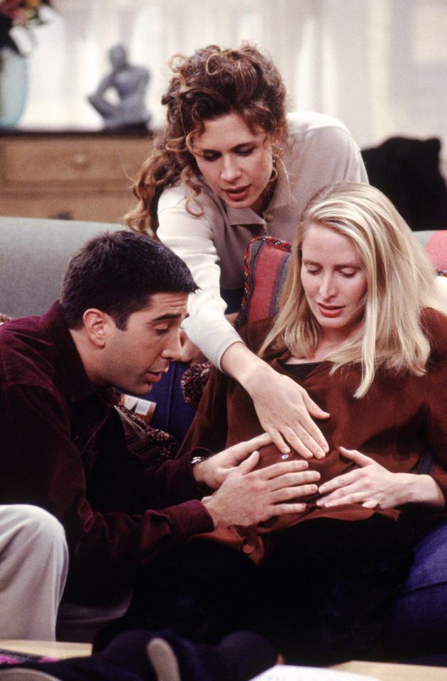 Still from *Friends* showing Ross, Carol, and Susan touching Carol's pregnant belly.