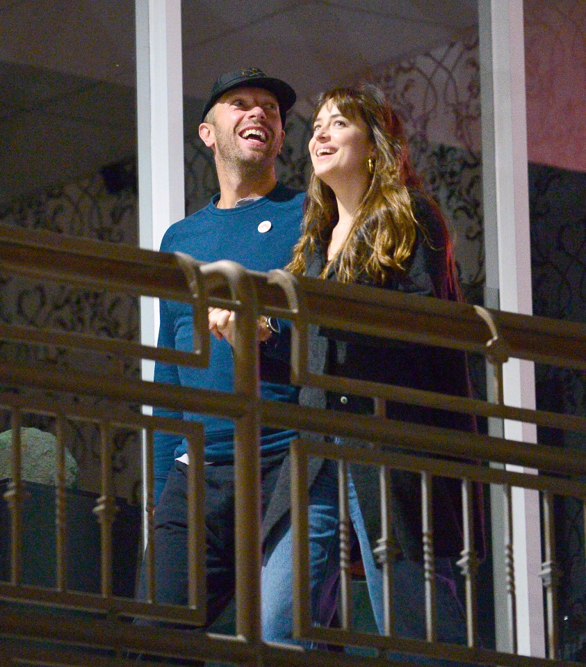 Dakota Johnson and Chris Martin on a balcony.