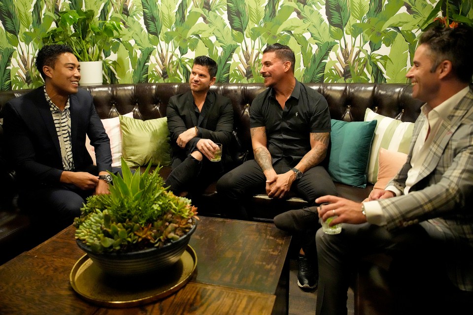 Four men sitting on a couch, talking.
