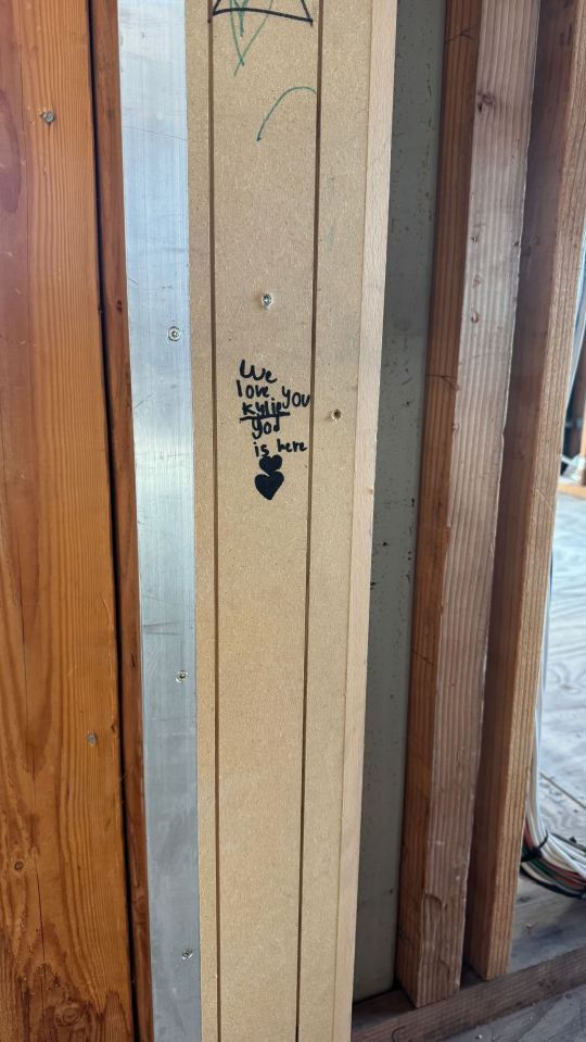 Graffiti on a wall during construction that reads "We love you Kylie God is here" and includes a heart.