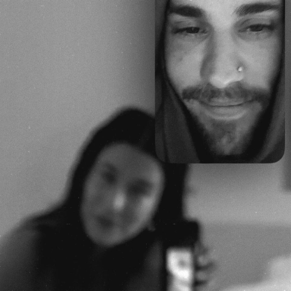Black and white photo of Justin Bieber in a selfie, with a blurred figure in the foreground.