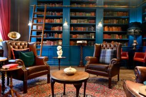 A room with book-filled shelves and leather armchairs