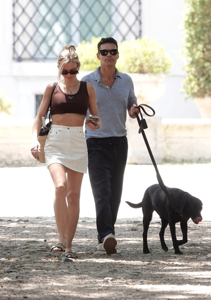 Ryan Seacrest and his girlfriend walking a dog.