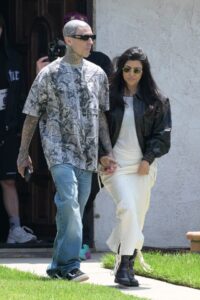 Kourtney Kardashian and Travis Barker holding hands while walking.