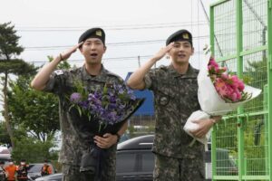 K-pop band BTS members RM, left, and V salute after being discharged from a mandatory military service in Chuncheon, South Korea, on Tuesday.