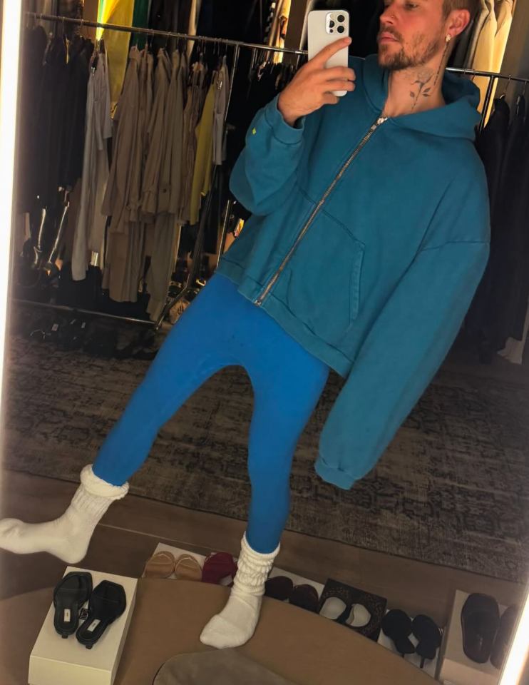 Justin Bieber taking a selfie in blue leggings and a teal zip-up hoodie.