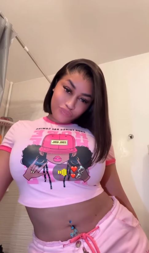 Mulher em blusa rosa e calças.