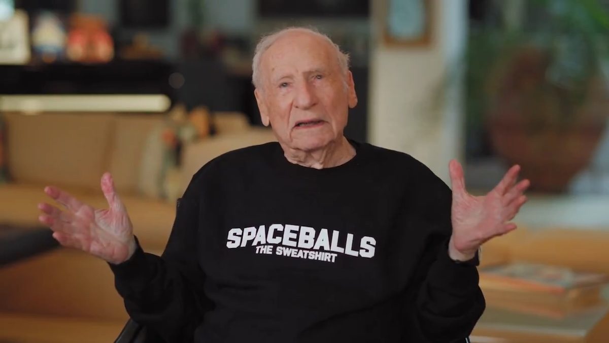 Mel Brooks with his arms held out wide with a Spaceballs The Sweatshirt on
