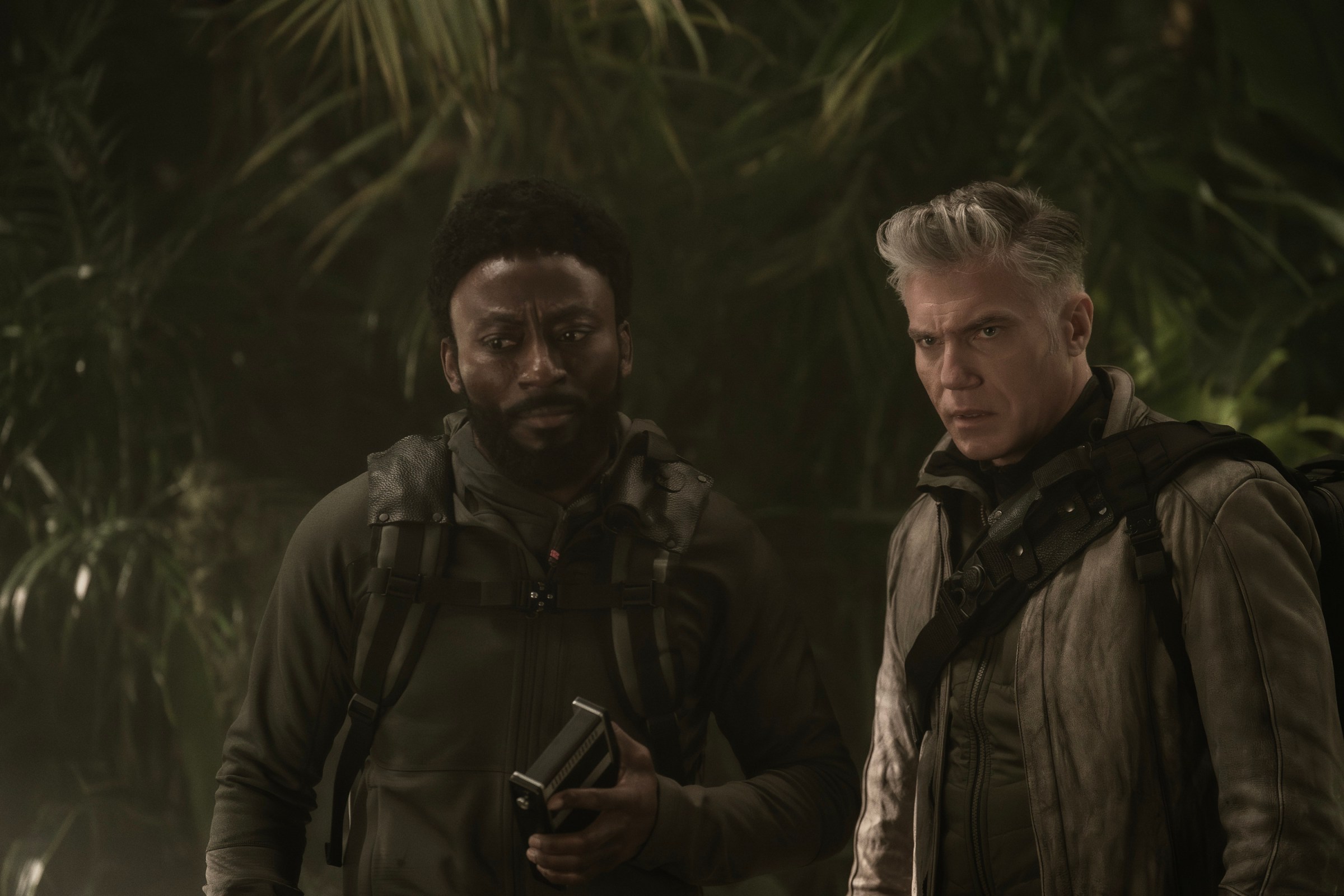 Babs Olusanmokun as Dr. M’Benga and Anson Mount as Capt. Pike stand in a tropical forest looking concerned in Strange New Worlds.
