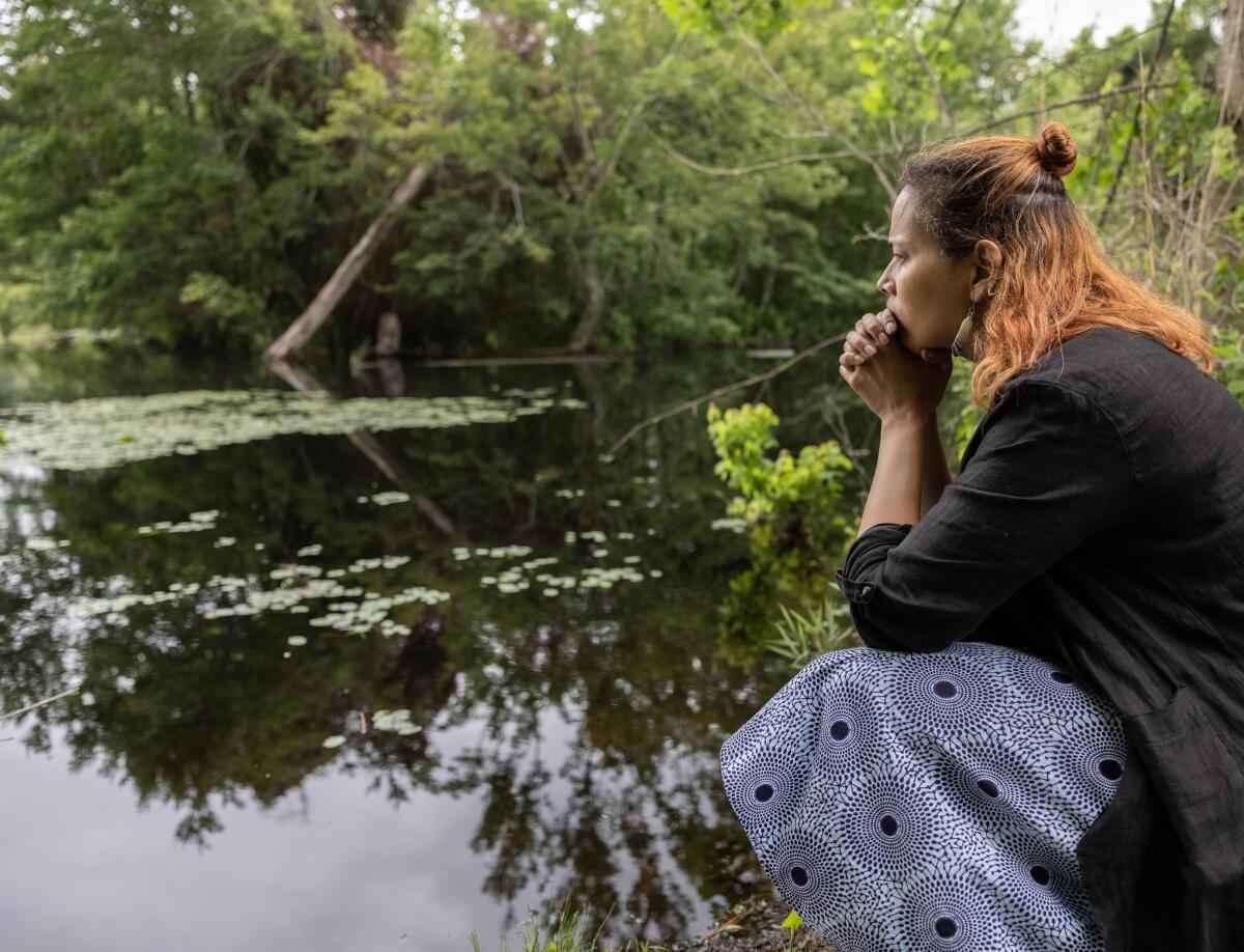 Woman in a dress crouching by a river