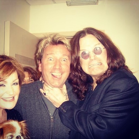 Ozzy Osbourne playfully choking a man while two women look on.