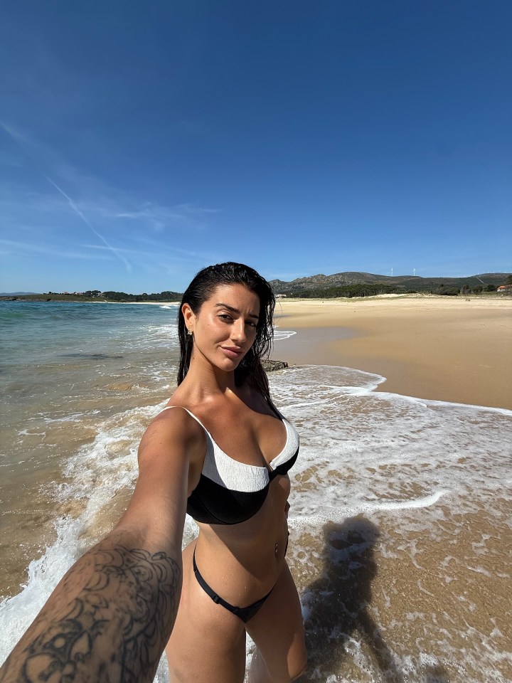 Woman sunbathing in a black and white bikini on a beach.