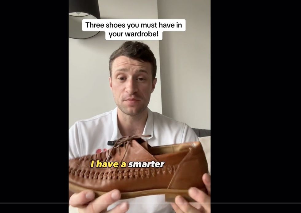 Paul, o podólogo, segurando sapatos de barco de couro marrom