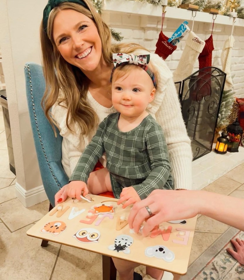 Woman and toddler playing with a wooden alphabet puzzle.