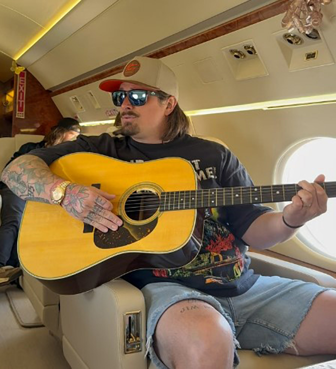 HARDY playing an acoustic guitar on a private jet.