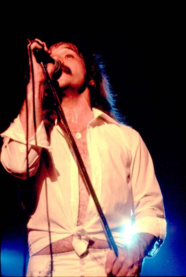 Terry Luttrell of Starcastle singing into a microphone on stage.