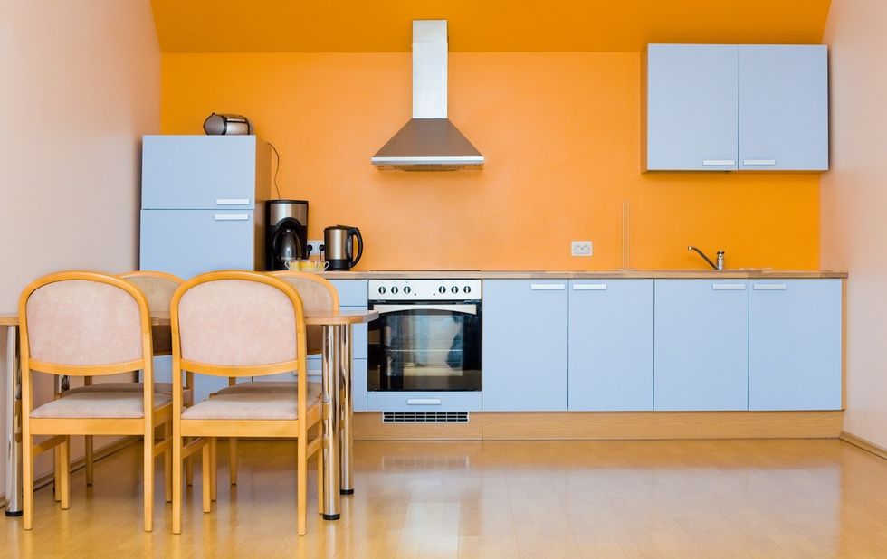 Uma cozinha contemporânea com armários azuis claros e paredes laranja