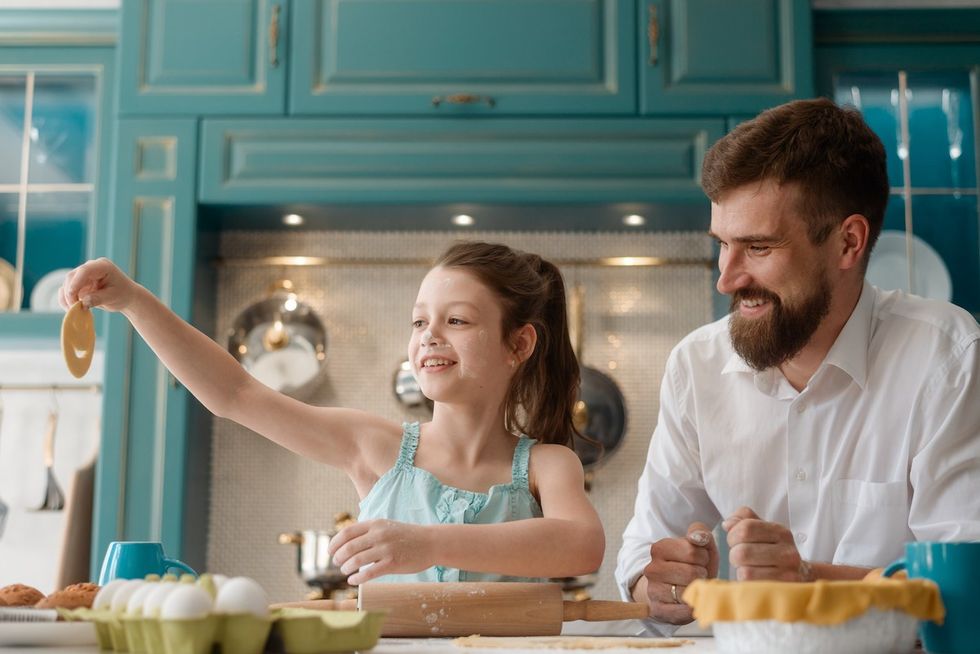 Pai e filha fazendo biscoitos em sua cozinha, que é uma cor cerceta.