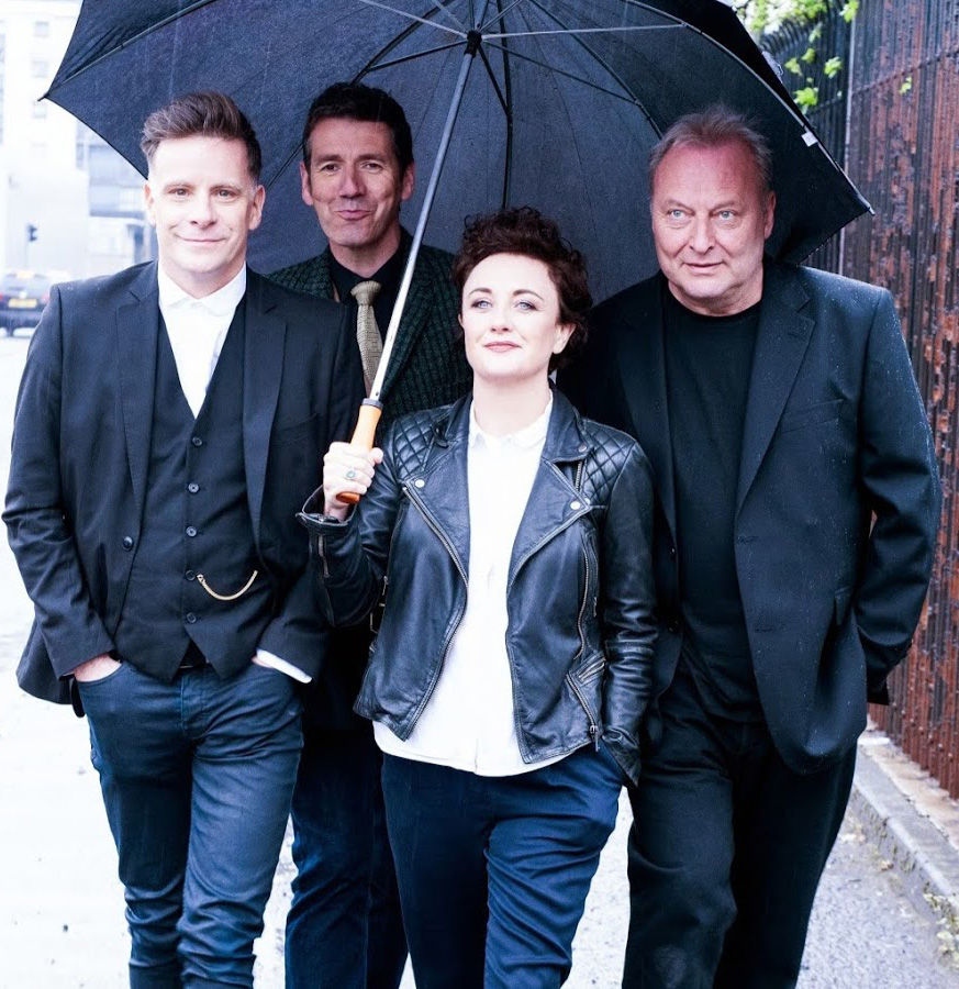 Deacon Blue band members walking under an umbrella.