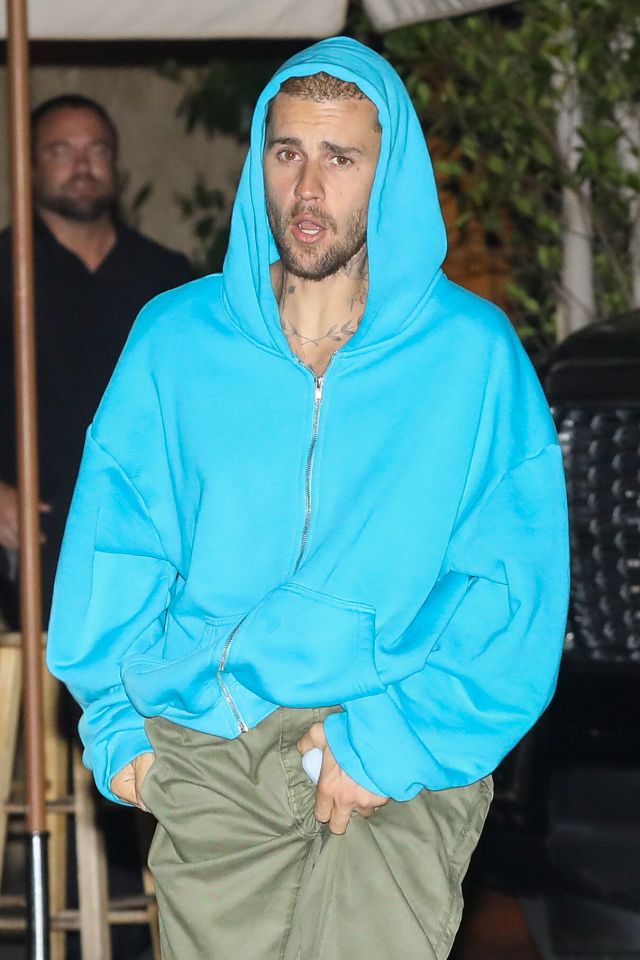 Justin Bieber wearing a bright blue hoodie outside a restaurant.