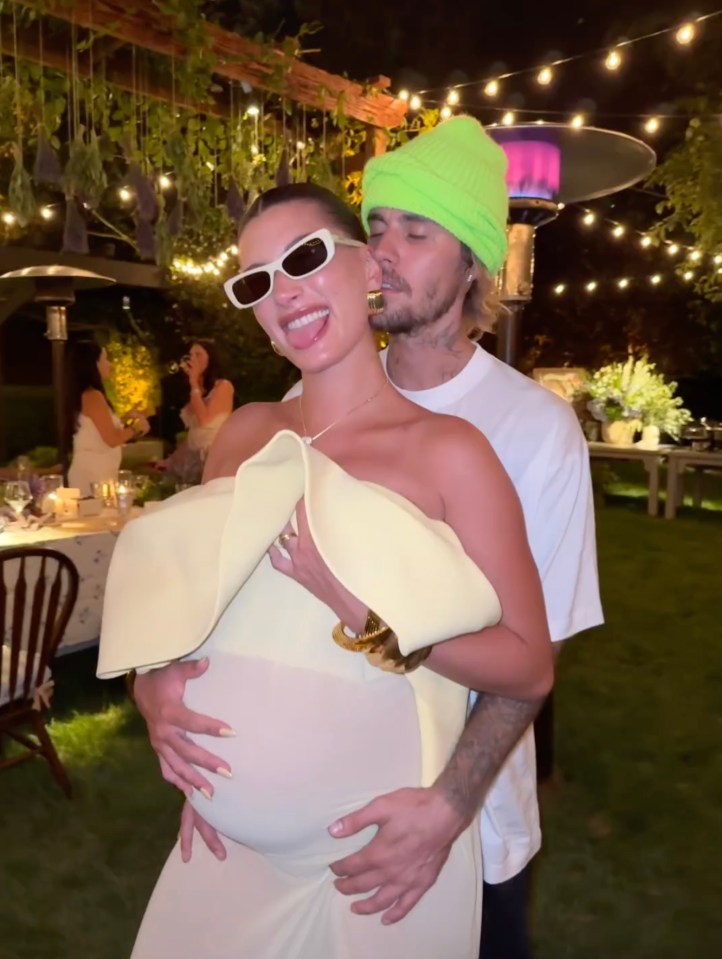 Hailey Bieber and Justin Bieber at an outdoor event, Hailey showing her baby bump.