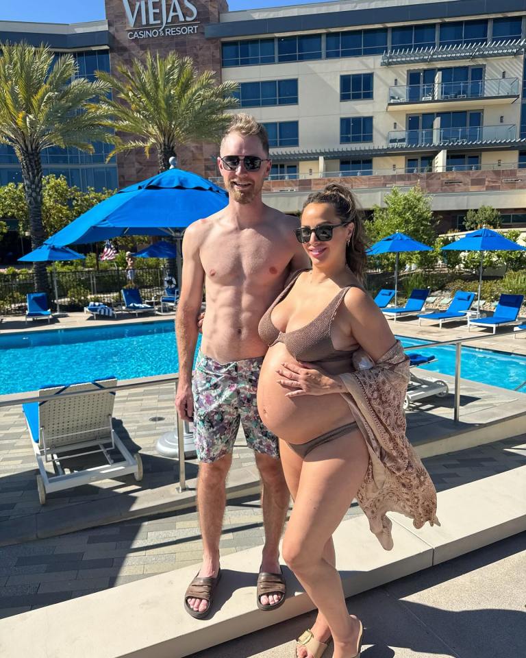 Pregnant woman and man by a resort pool.