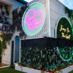 Casa Amor entrance with neon signs and greenery.