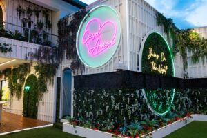 Casa Amor entrance with neon signs and greenery.