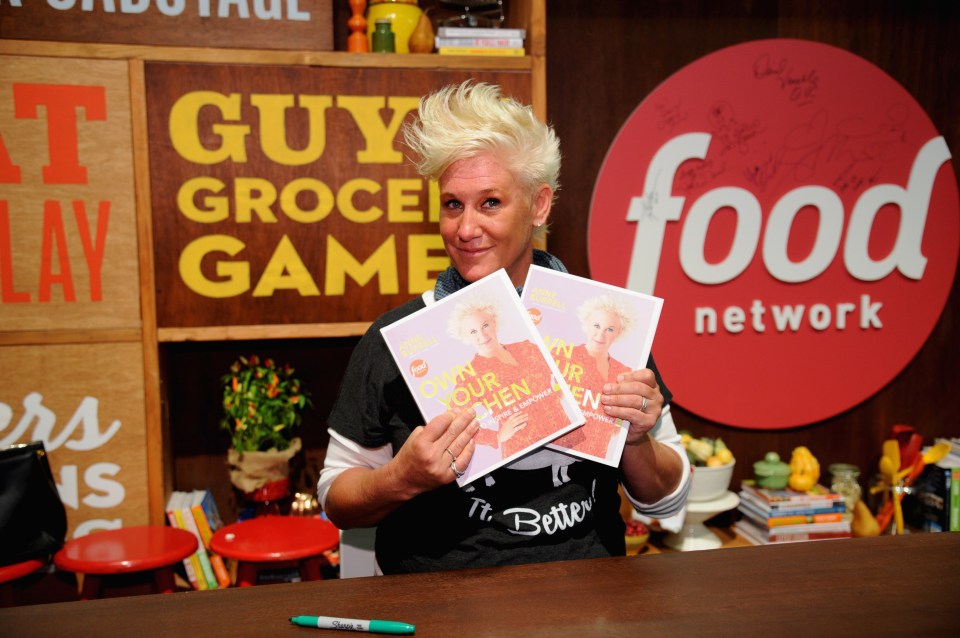 Chef Anne Burrell holding copies of her cookbook, "Own Your Kitchen."