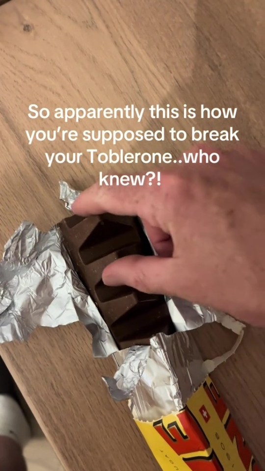 Hand snapping a Toblerone chocolate bar.