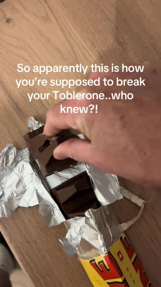 A hand snapping a Toblerone chocolate bar.